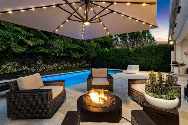 pool at dusk with an outdoor living space with a fire pit