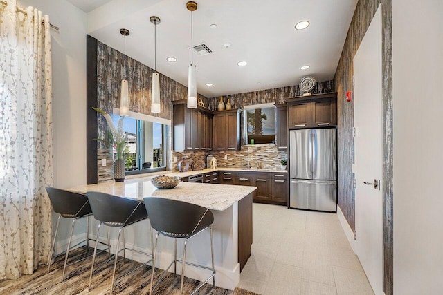 kitchen with dark brown cabinetry, stainless steel fridge, and kitchen peninsula