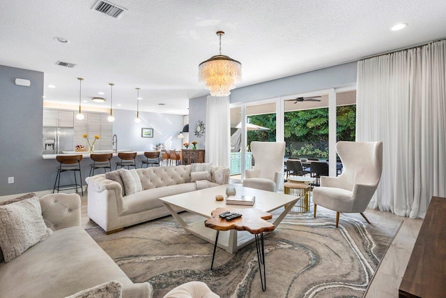 living room with ceiling fan with notable chandelier, sink, and a textured ceiling