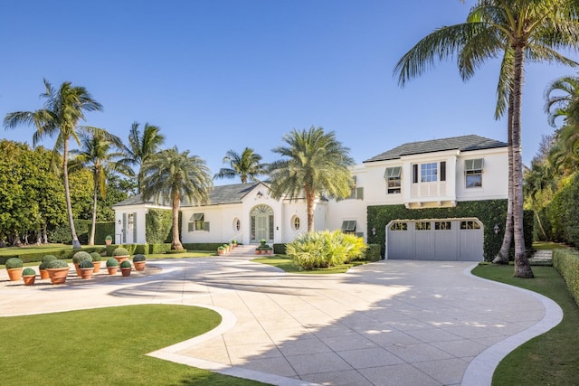 mediterranean / spanish home featuring a garage and a front lawn