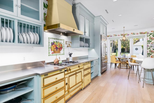 kitchen with stainless steel counters, french doors, wall chimney exhaust hood, pendant lighting, and appliances with stainless steel finishes