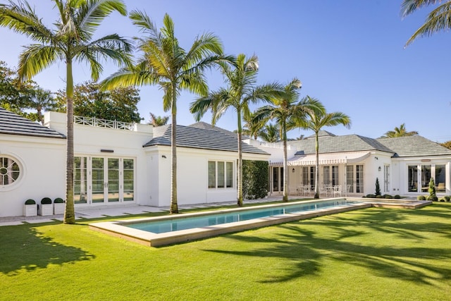 rear view of house featuring french doors and a lawn