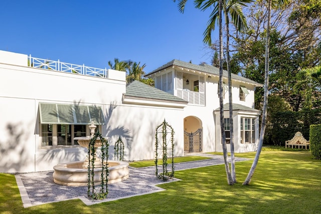 back of house with a balcony and a lawn