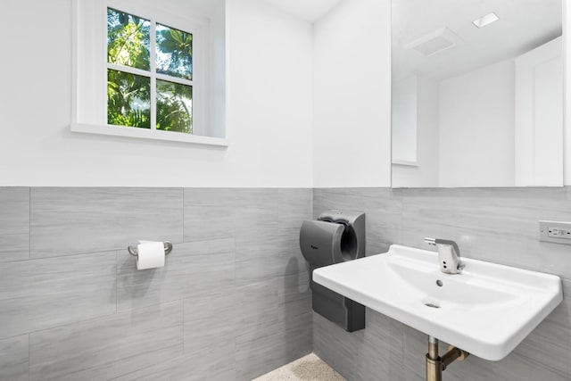 bathroom featuring sink and tile walls