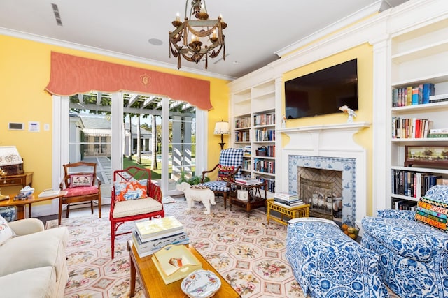 living room with a chandelier, built in features, ornamental molding, and a tiled fireplace