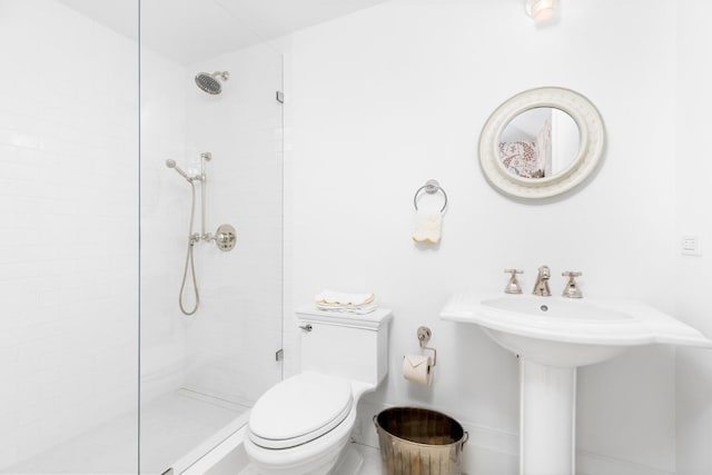 bathroom with sink, toilet, and tiled shower