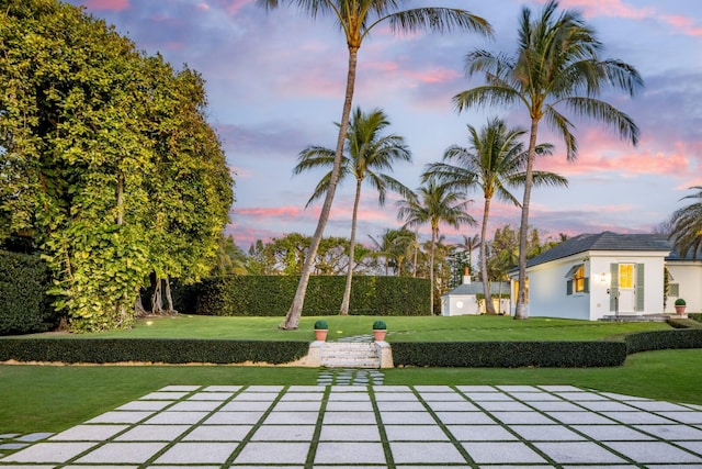 patio terrace at dusk featuring a yard and an outdoor structure