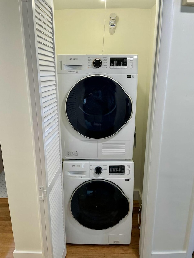 clothes washing area featuring hardwood / wood-style floors and stacked washer and dryer