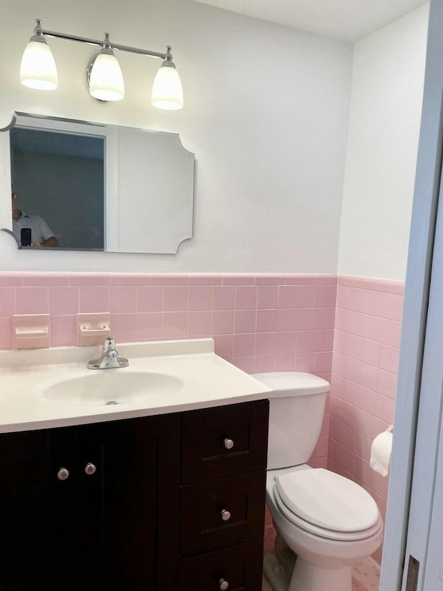 bathroom with vanity, toilet, and tile walls