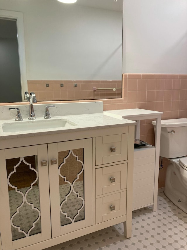 bathroom featuring tile patterned flooring, vanity, toilet, and tile walls