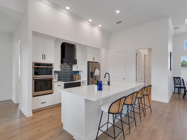 kitchen featuring white cabinetry, a large island, stainless steel appliances, and premium range hood