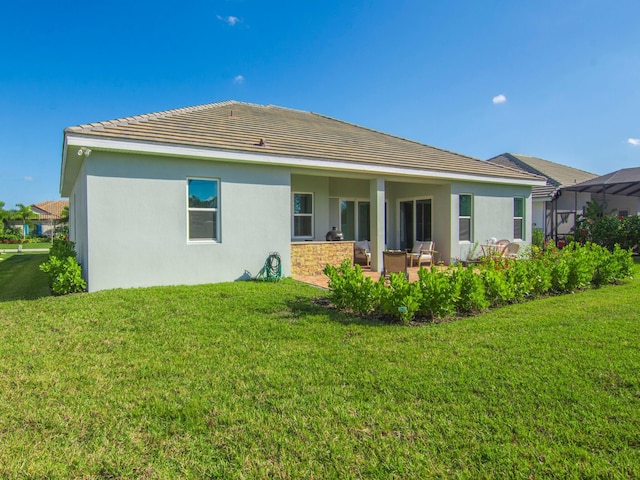 rear view of house with a patio and a lawn