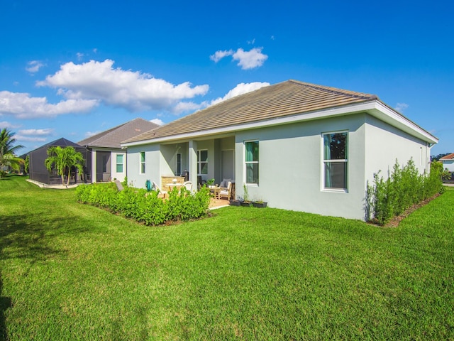 rear view of house featuring a sunroom, a yard, and a patio