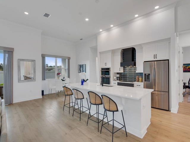 kitchen with sink, stainless steel fridge, a large island, a kitchen bar, and white cabinetry