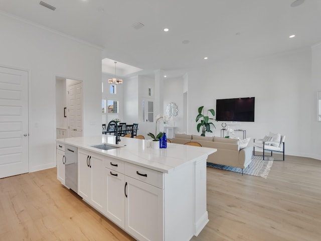 kitchen featuring white cabinets, light stone counters, a center island with sink, and sink