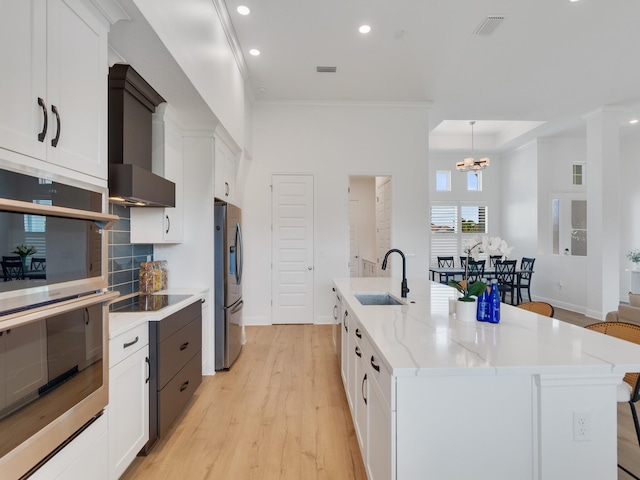 kitchen featuring stainless steel refrigerator with ice dispenser, white cabinetry, a spacious island, and sink