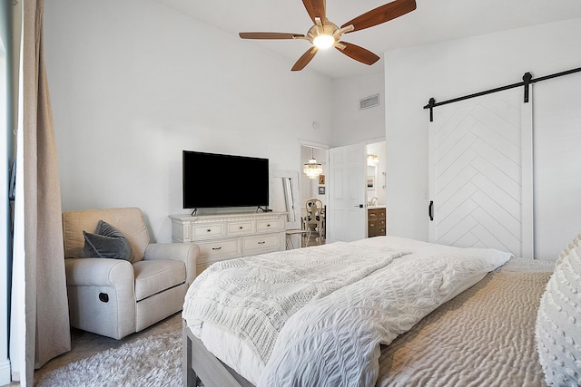 bedroom featuring vaulted ceiling, ensuite bath, ceiling fan, and a barn door