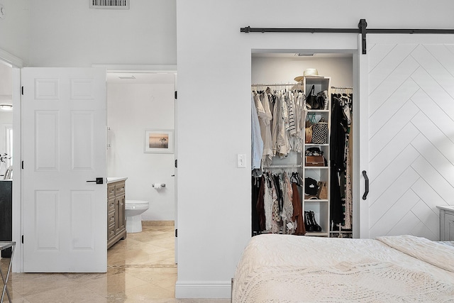 bedroom featuring ensuite bath, a closet, a barn door, and a spacious closet