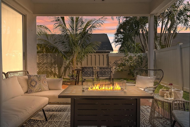 balcony at dusk with an outdoor living space with a fire pit and a patio area