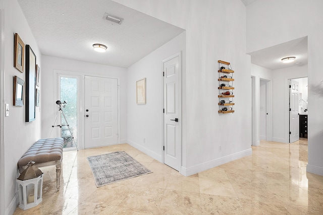 entryway featuring visible vents, a textured ceiling, and baseboards