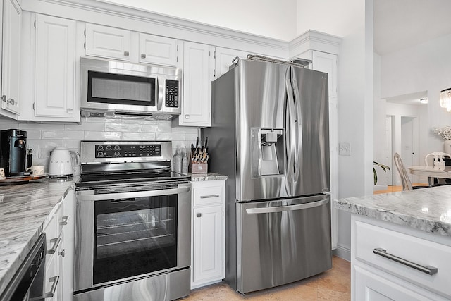 kitchen featuring white cabinetry, appliances with stainless steel finishes, light stone counters, and backsplash