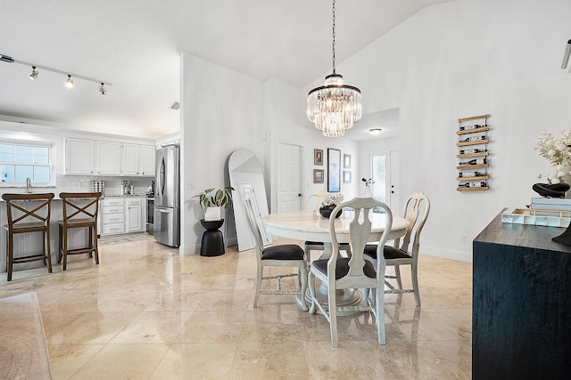 dining area with a notable chandelier, baseboards, and high vaulted ceiling