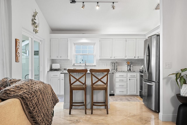 kitchen with stainless steel appliances, white cabinets, tasteful backsplash, and light stone countertops