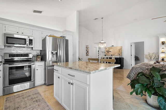 kitchen with a kitchen island, white cabinets, appliances with stainless steel finishes, and lofted ceiling