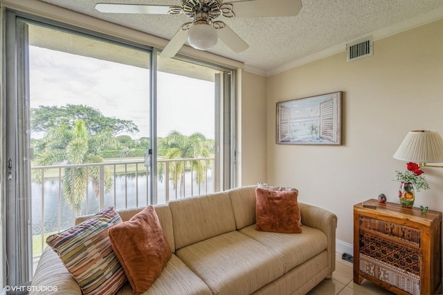 tiled living room featuring crown molding, a water view, ceiling fan, and a textured ceiling