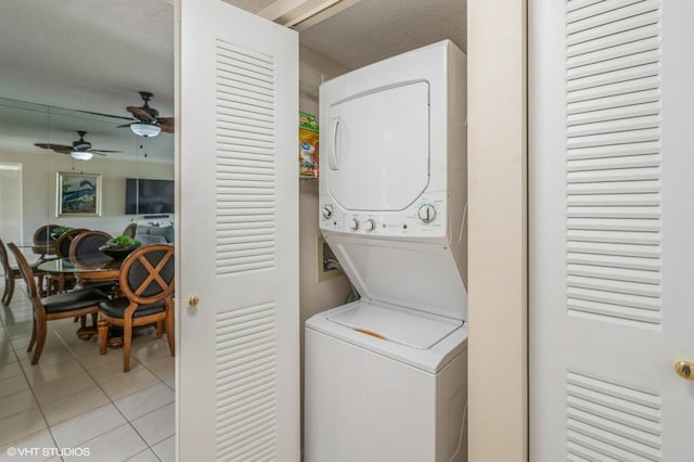 laundry area featuring ceiling fan, stacked washing maching and dryer, and light tile patterned floors