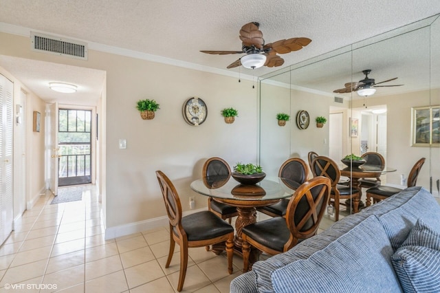 tiled dining space featuring ornamental molding, ceiling fan, and a textured ceiling