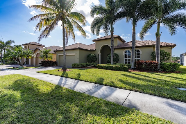 mediterranean / spanish-style home featuring a garage and a front lawn