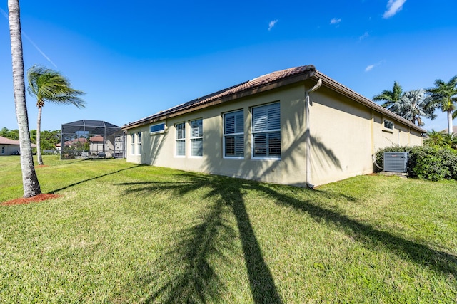 view of side of home featuring a lanai, central air condition unit, and a yard