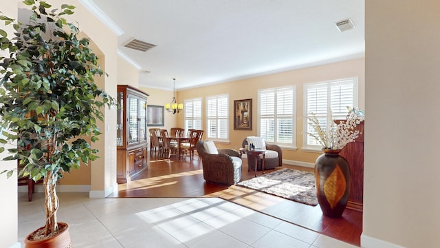 living room featuring a notable chandelier, light tile patterned floors, and crown molding