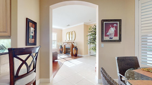 hallway with light tile patterned floors and crown molding