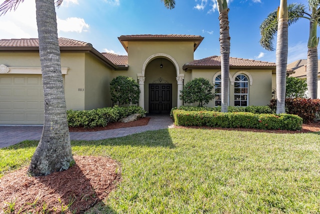 mediterranean / spanish home with a garage and a front lawn