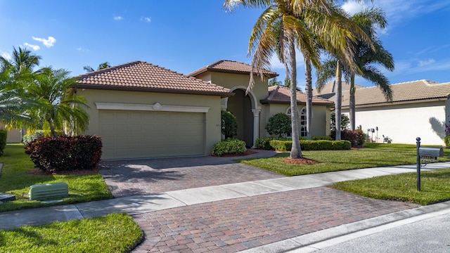 mediterranean / spanish home featuring a garage and a front lawn