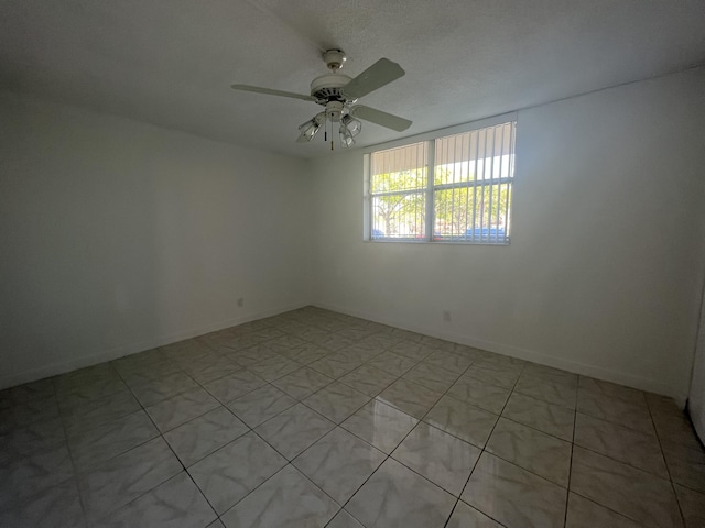 tiled empty room featuring ceiling fan