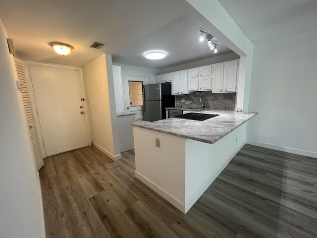 kitchen featuring white cabinetry, dark hardwood / wood-style floors, kitchen peninsula, refrigerator, and decorative backsplash