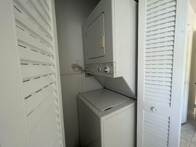 laundry area with stacked washer / dryer and light tile patterned floors