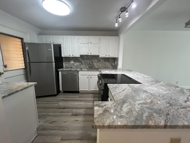 kitchen with kitchen peninsula, appliances with stainless steel finishes, white cabinetry, and light stone counters