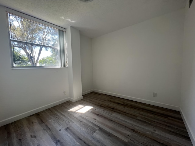 empty room featuring a textured ceiling and dark hardwood / wood-style floors