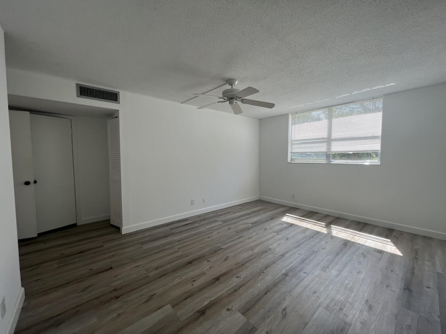 unfurnished bedroom with a textured ceiling, ceiling fan, dark wood-type flooring, and a closet