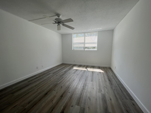 empty room with a textured ceiling, ceiling fan, and dark hardwood / wood-style floors