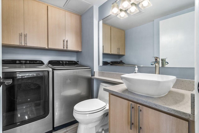 clothes washing area featuring sink, light hardwood / wood-style floors, and independent washer and dryer