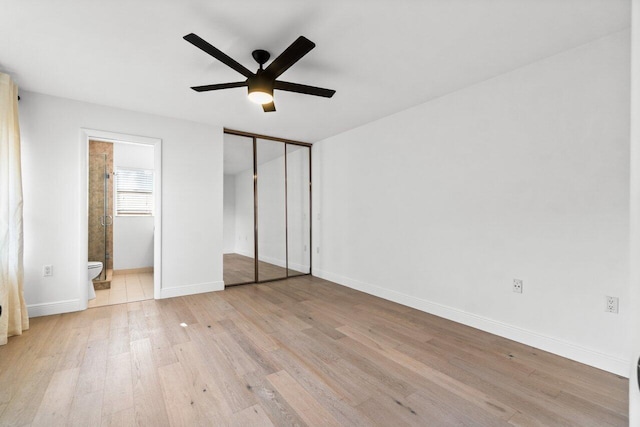 unfurnished bedroom with a closet, ensuite bath, ceiling fan, and light hardwood / wood-style flooring