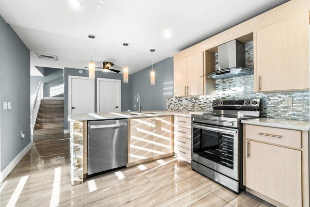 kitchen featuring kitchen peninsula, stove, light brown cabinetry, sink, and pendant lighting