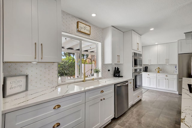 kitchen with light stone counters, white cabinetry, stainless steel appliances, and tasteful backsplash