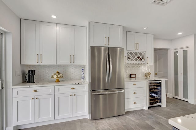 kitchen featuring backsplash, stainless steel refrigerator, white cabinets, and wine cooler