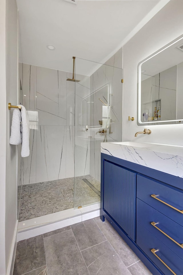 bathroom with tile patterned flooring, vanity, and tiled shower